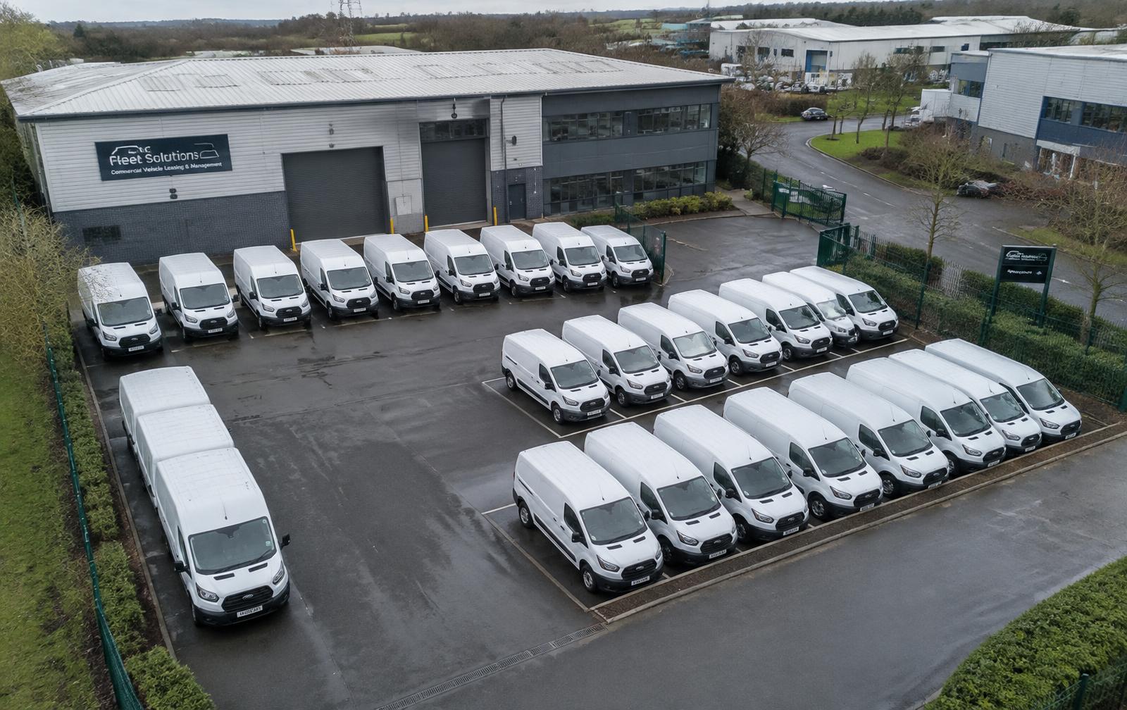 Fleet of white vans at a business depot